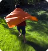 Young boy running with his cape billowing behind